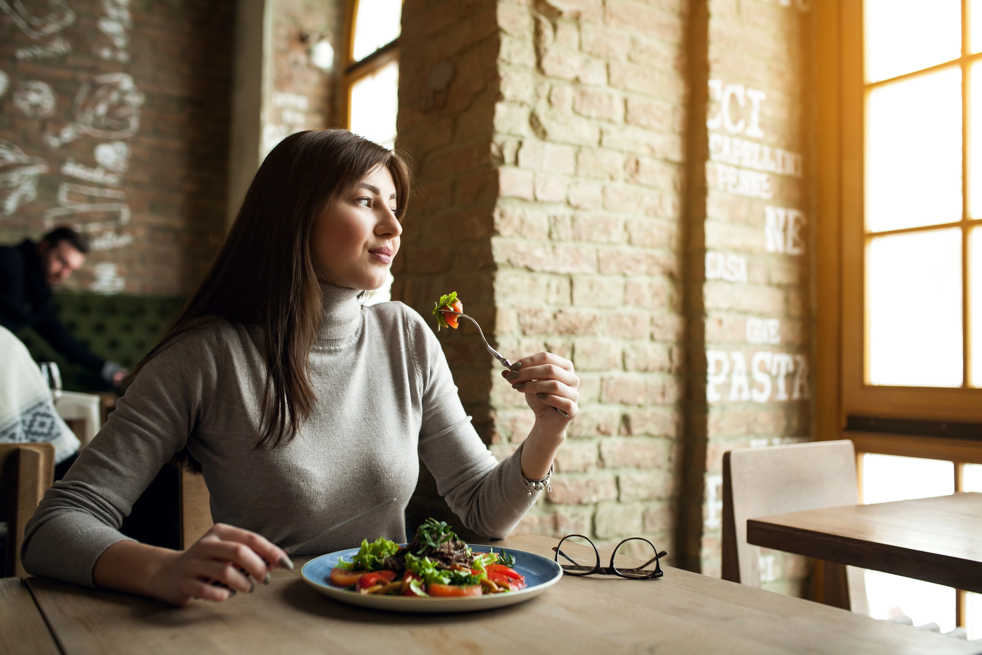 mulher segurando um garfo em cima de uma mesa de restaurante