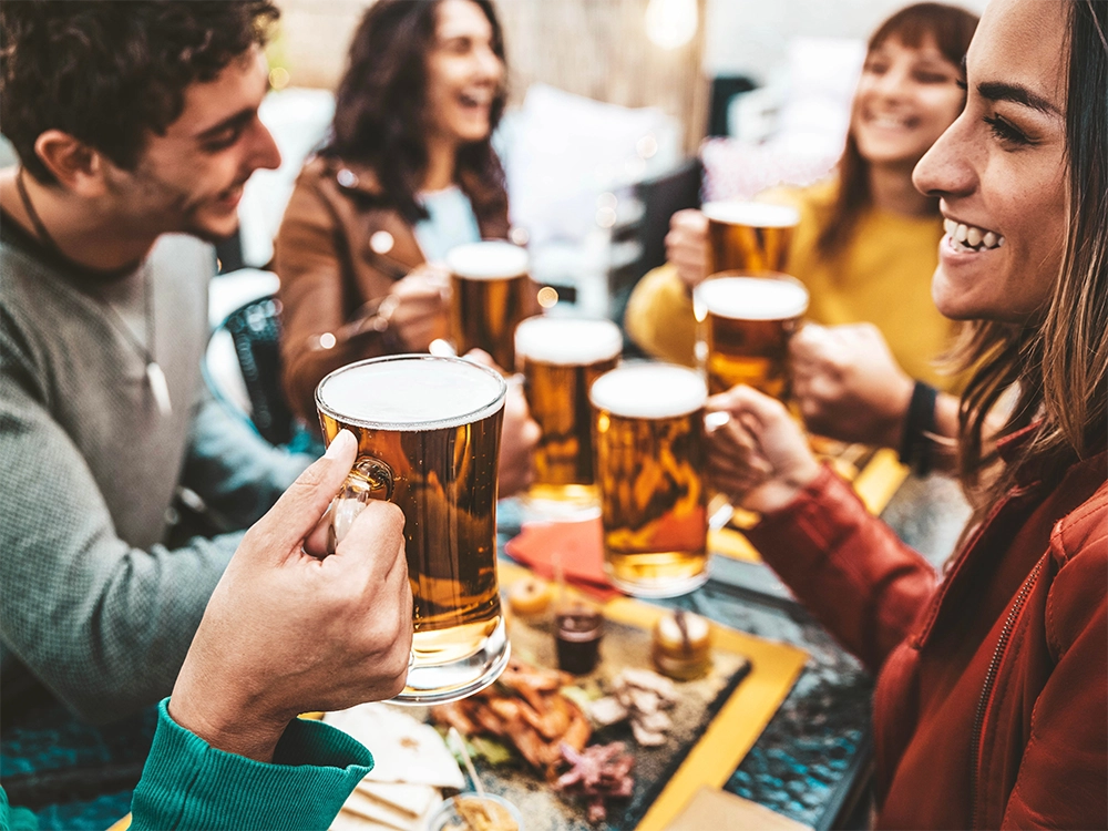 pessoas sentados numa mesa com cerveja na mao em um happy hour